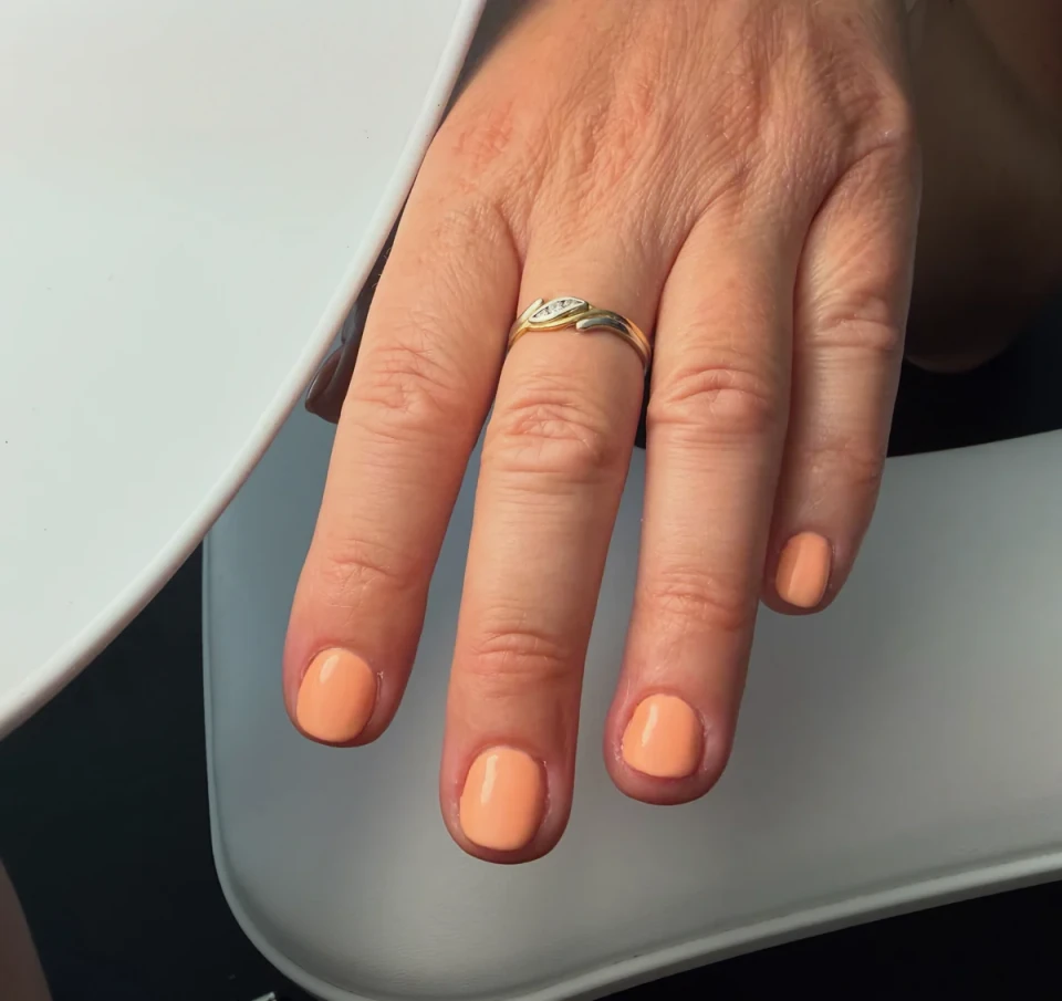 Eén hand met perzikkleurige BIAB-nagels, aangebracht bij Elé-chique.