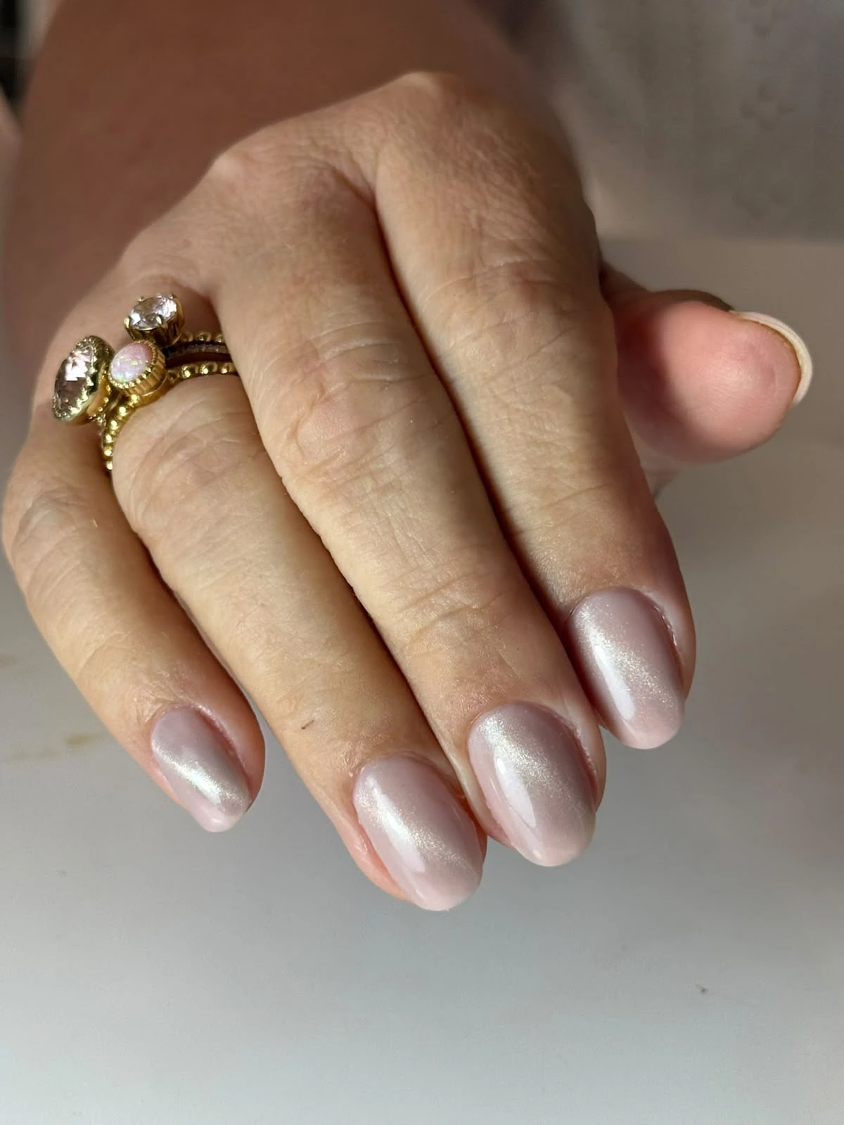 Lichtroze fibergelnagels met een subtiele cat-eye-afwerking.