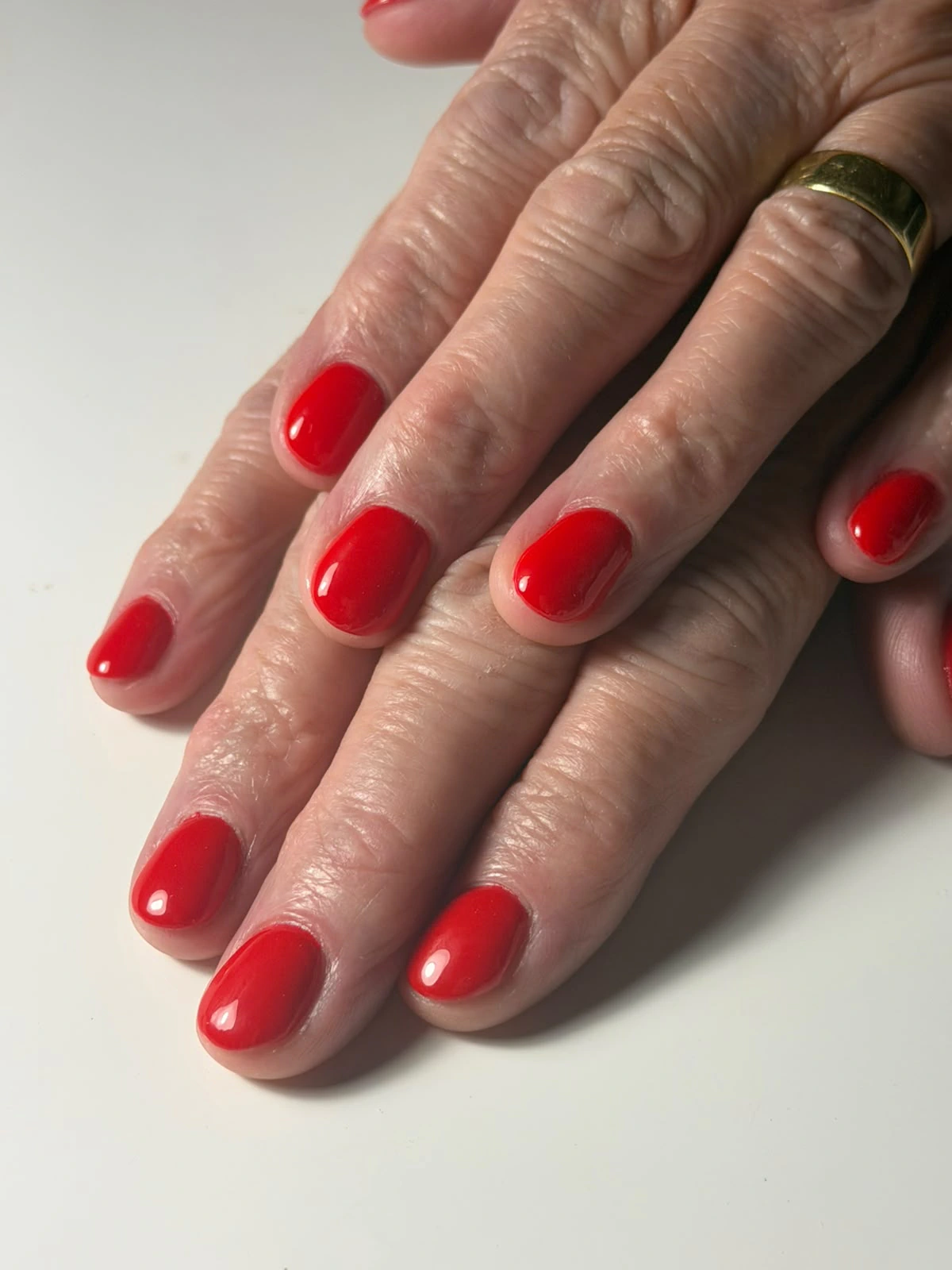 Twee handen met rode BIAB-nagels.